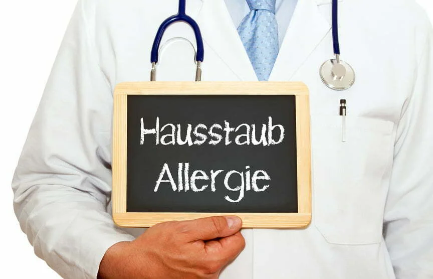 hausstauballergie – hausstauballergie,hausstaubmilbenallergie,hausstaubmilbenallergie was tun,hausstauballergie was tun Arzt hält ein Schild mit der Aufschrift Hausstauballergie